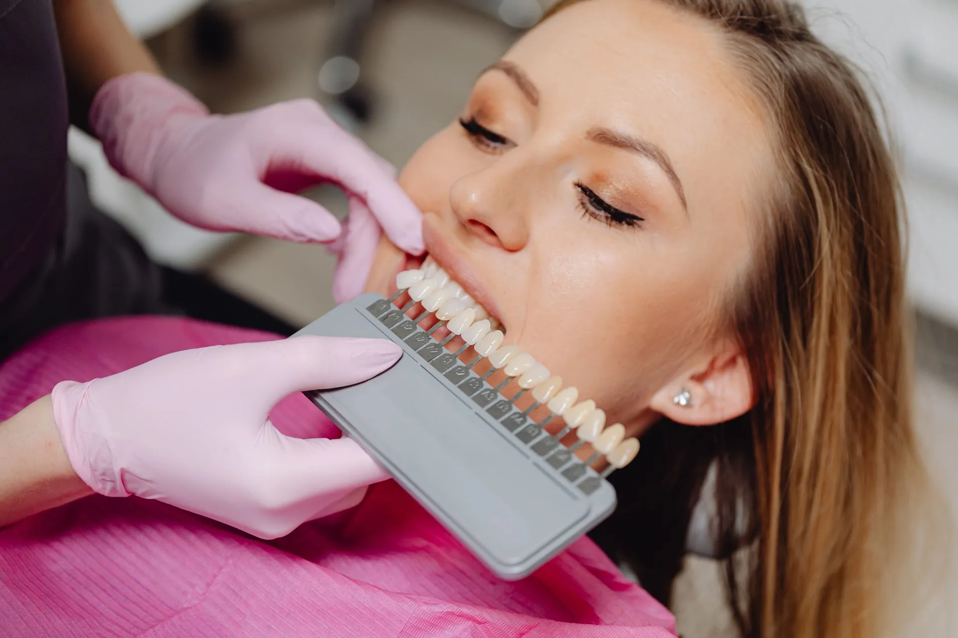 Odontóloga comparando el tono de los dientes de una paciente con una guía de color